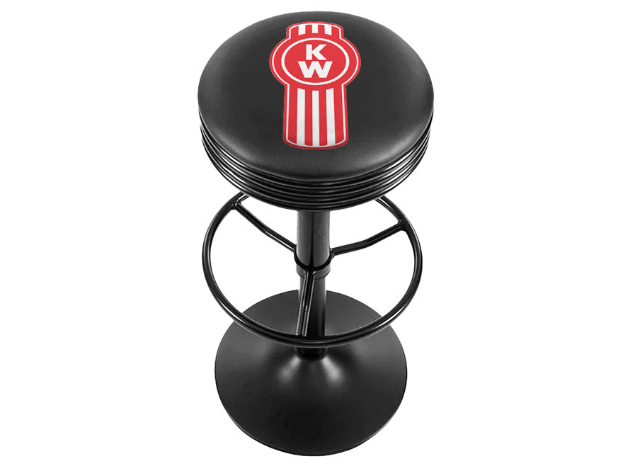 The BARSTOOL KW RED BUG is a black Kenworth barstool with a round cushioned seat featuring a red and white KW logo, a metal frame, and circular footrest.