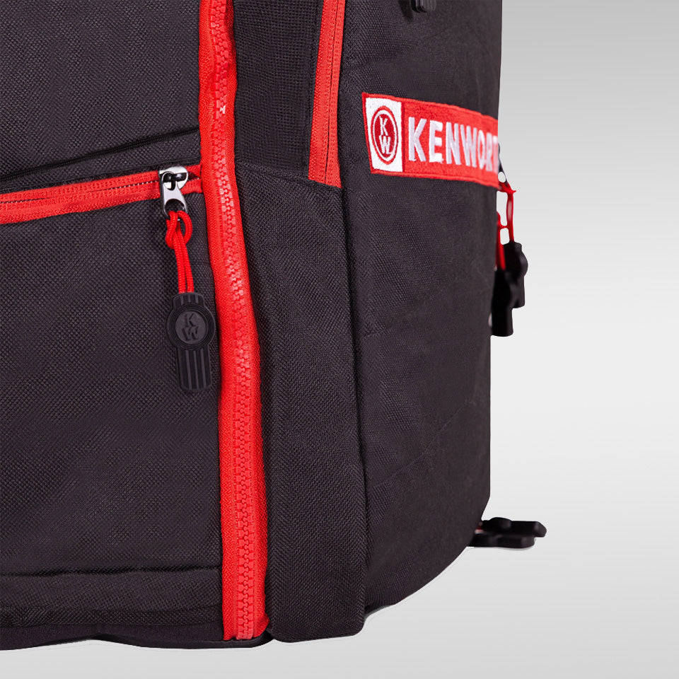 Close-up of a BACKPACK KW with bright red zippers and trim, featuring the Kenworth logo patch. This organized gear offers multiple compartments and rugged fabric—ideal for everyday adventures.