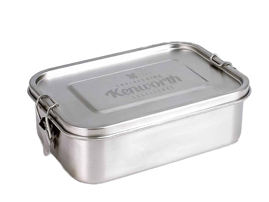 The LUNCH BOX KW S/S is a rectangular, food-grade stainless steel container with metal clasps on the lid and "Kenworth Excellence" engraved on top.