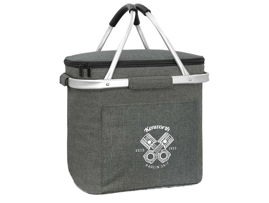 The COOLER KW BASKET 16L is a gray insulated picnic basket with a zippered lid, two foldable aluminum handles with black grips, a collapsible frame, and a front pocket showcasing a white Kenworth logo and engine graphic.