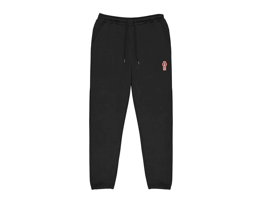 SWEATPANT KW MENS BLACK features a relaxed fit, elastic waistband with drawstring, side pockets, and a red and white patch logo on the left thigh. Shown in black on a white background.