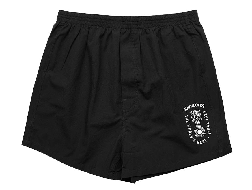 The BOXER SHORT KW MENS are comfortable black boxers featuring an elastic waistband, front pleats, and a white piston graphic with "Kenworth The Best In The World Since 1923" on the lower left leg—ideal for daily wear.