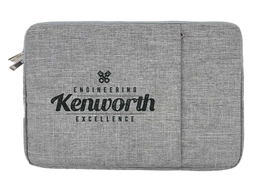 The BAG KW LAPTOP/IPAD is a grey fabric sleeve with foam padding, front pocket, and zipper—fits 15” devices—and features "Engineering Kenworth Excellence" in black text on the front.