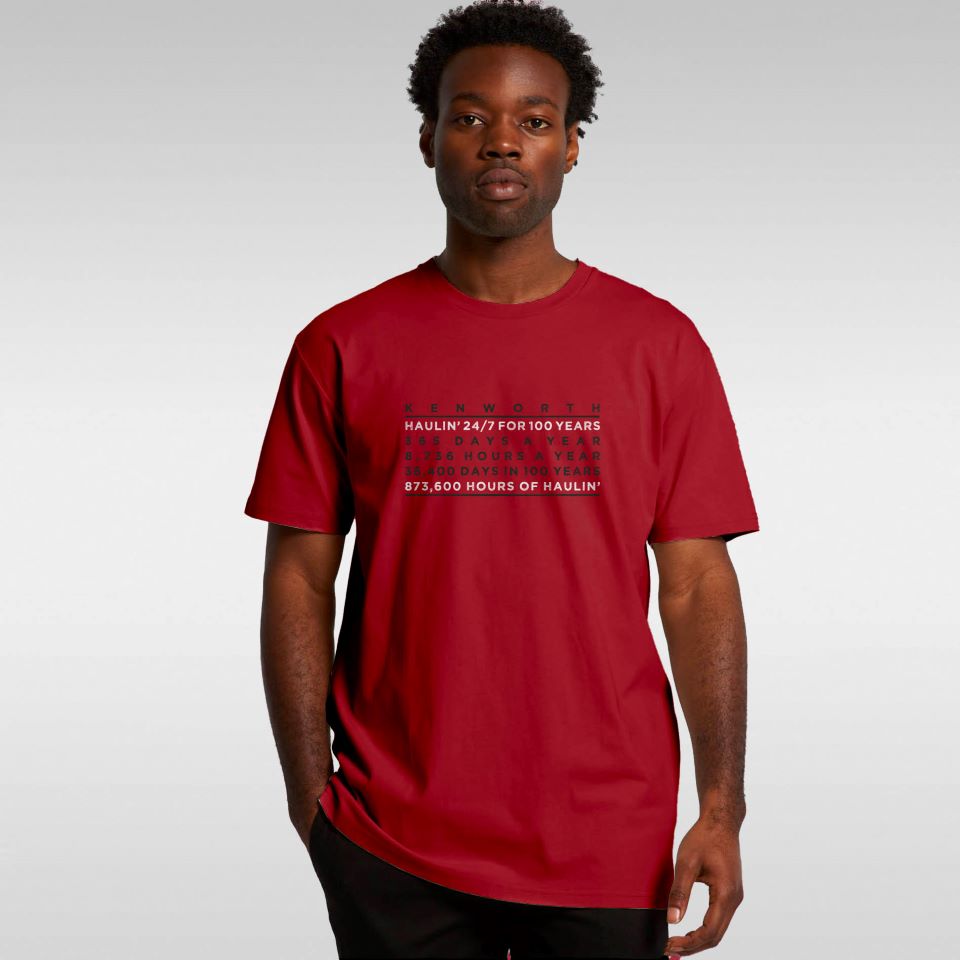 A man stands facing forward, wearing the TEE SHIRT KW HAULIN RED with front text. He has a neutral expression and is set against a plain light gray background, showcasing this classic everyday Kenworth tee.
