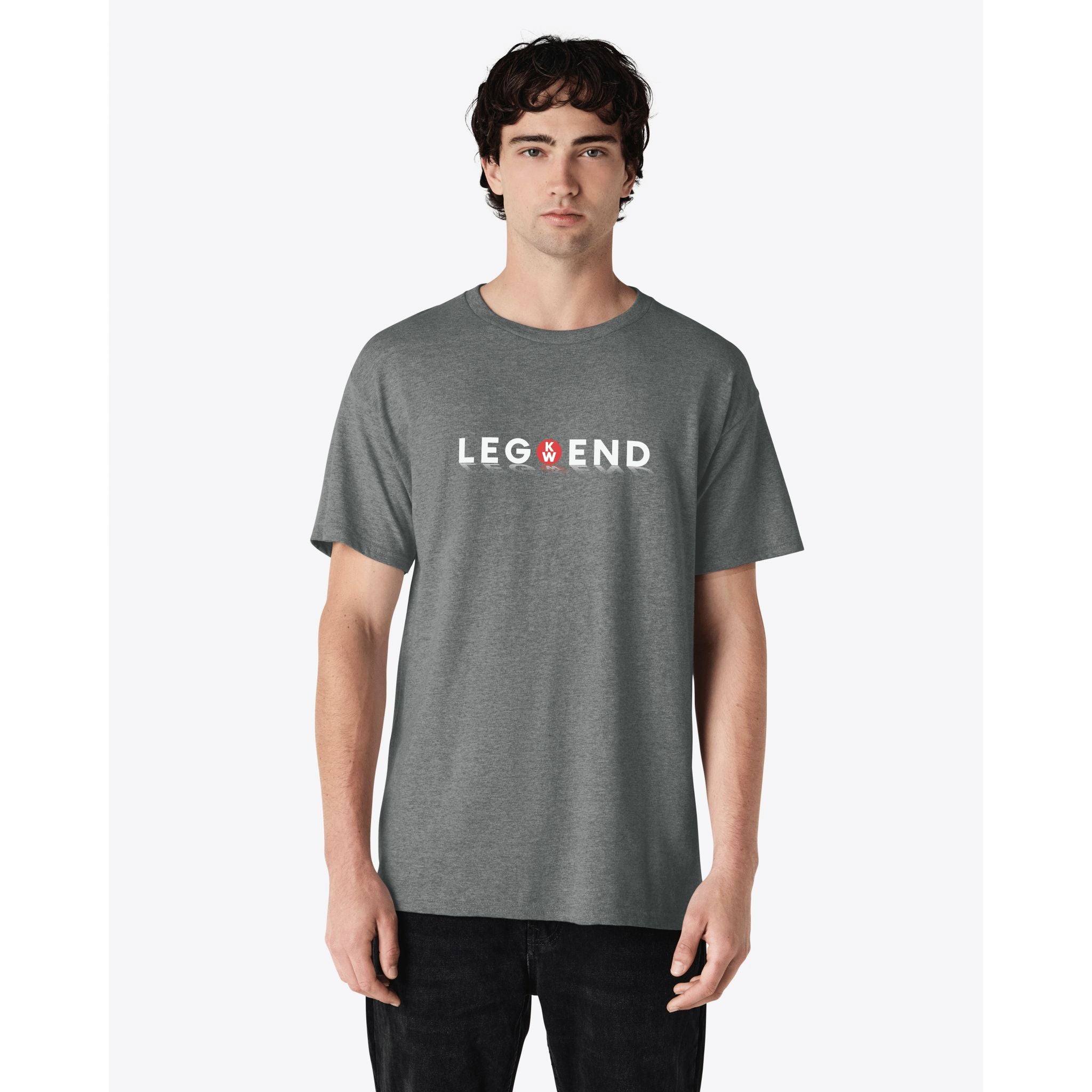 A young man models the TEE SHIRT KW LEGEND in grey, featuring a truck-inspired "LEGEND" design with the middle "E" replaced by a red hand symbol, standing against a plain white background.