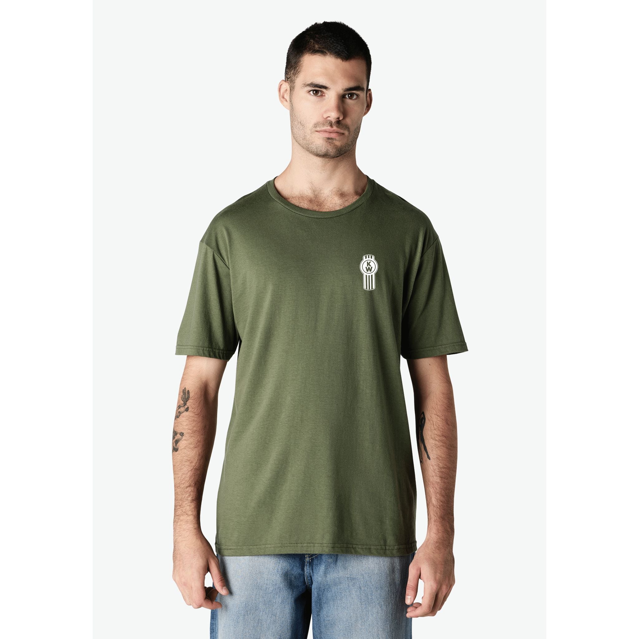 A man stands facing forward against a white background, wearing the TEE SHIRT KW NO1 GREEN with a small white graphic on the left chest and light blue jeans.