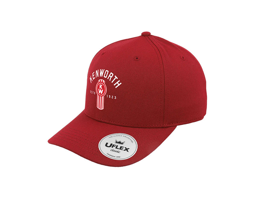 The CAP KW BUG RED is a red Kenworth cap with a curved brim, featuring the bold Kenworth logo and ESTD 1923 on the front. The bill has a round UFlex Classic sticker, highlighting its classic panel design.