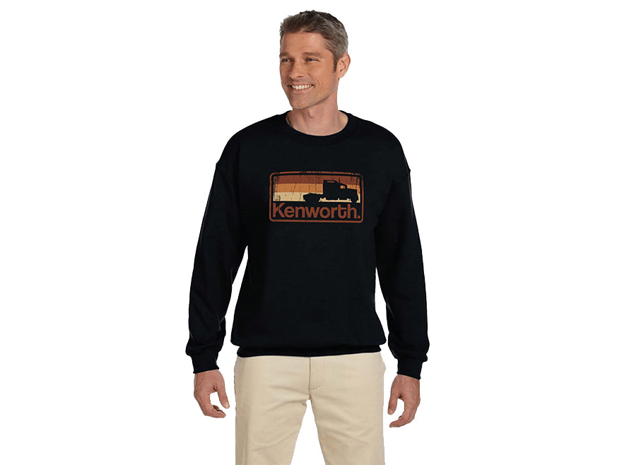 A smiling man with short hair wears the black SWEATSHIRT KW SHADOW featuring a retro Kenworth truck graphic and shadow logo, paired with light-colored pants, standing against a white background facing slightly to the side.