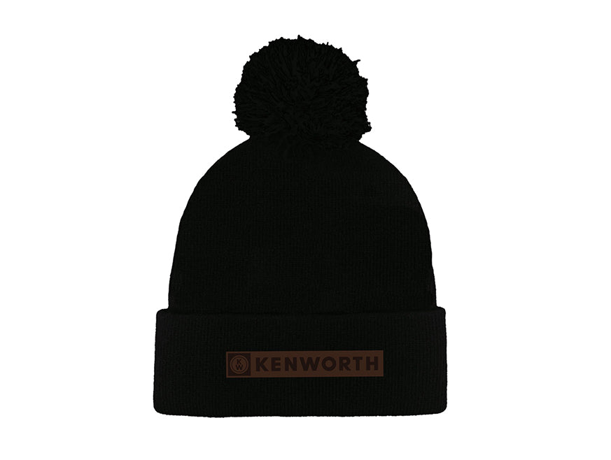 The BEANIE KW POMPOM BLACK features a black pompom, folded brim, and brown Kenworth patch—perfect for keeping warm in style.