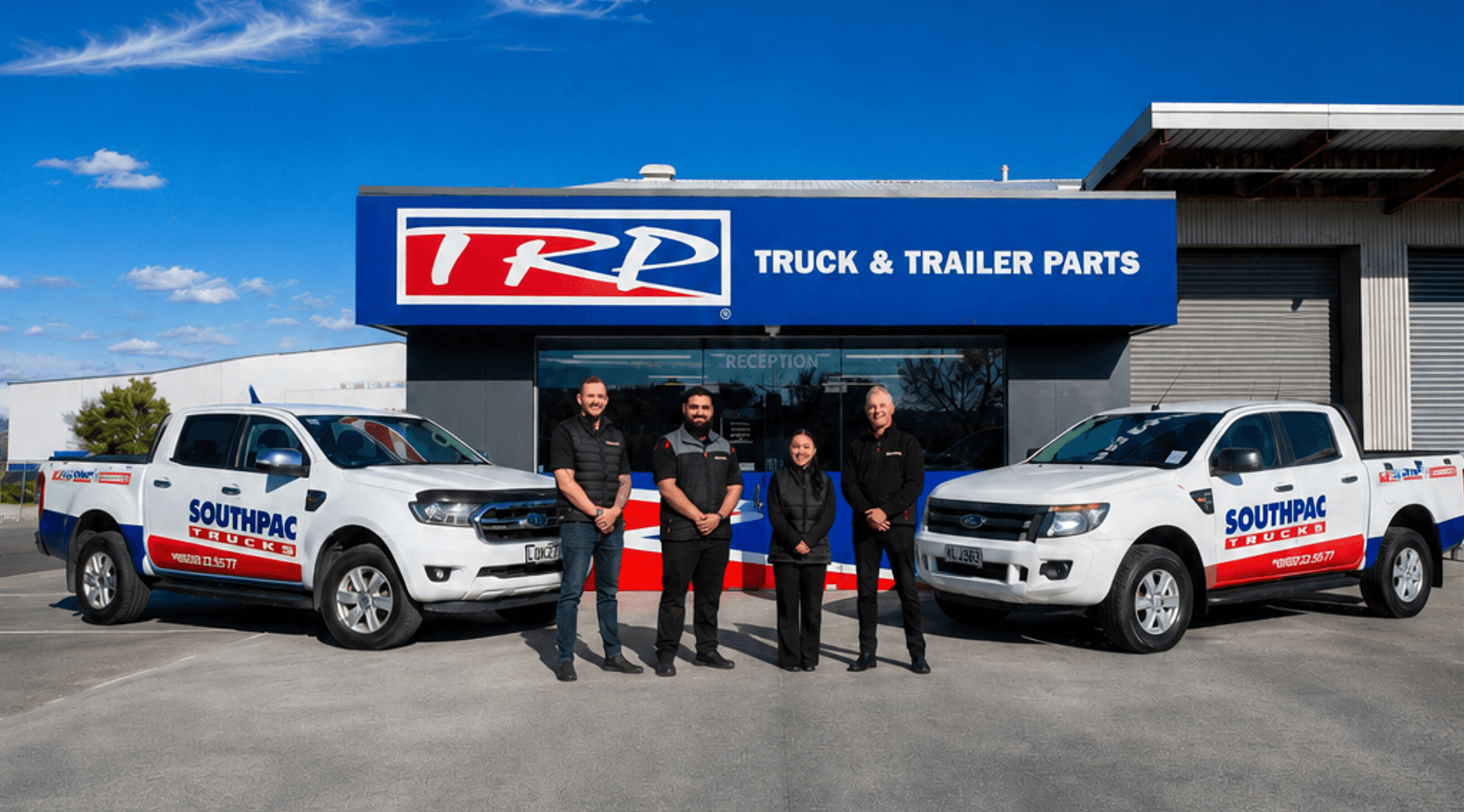 TRP Truck & Trailer Parts staff in front of their building with Southpac trucks parked outside on a sunny day.