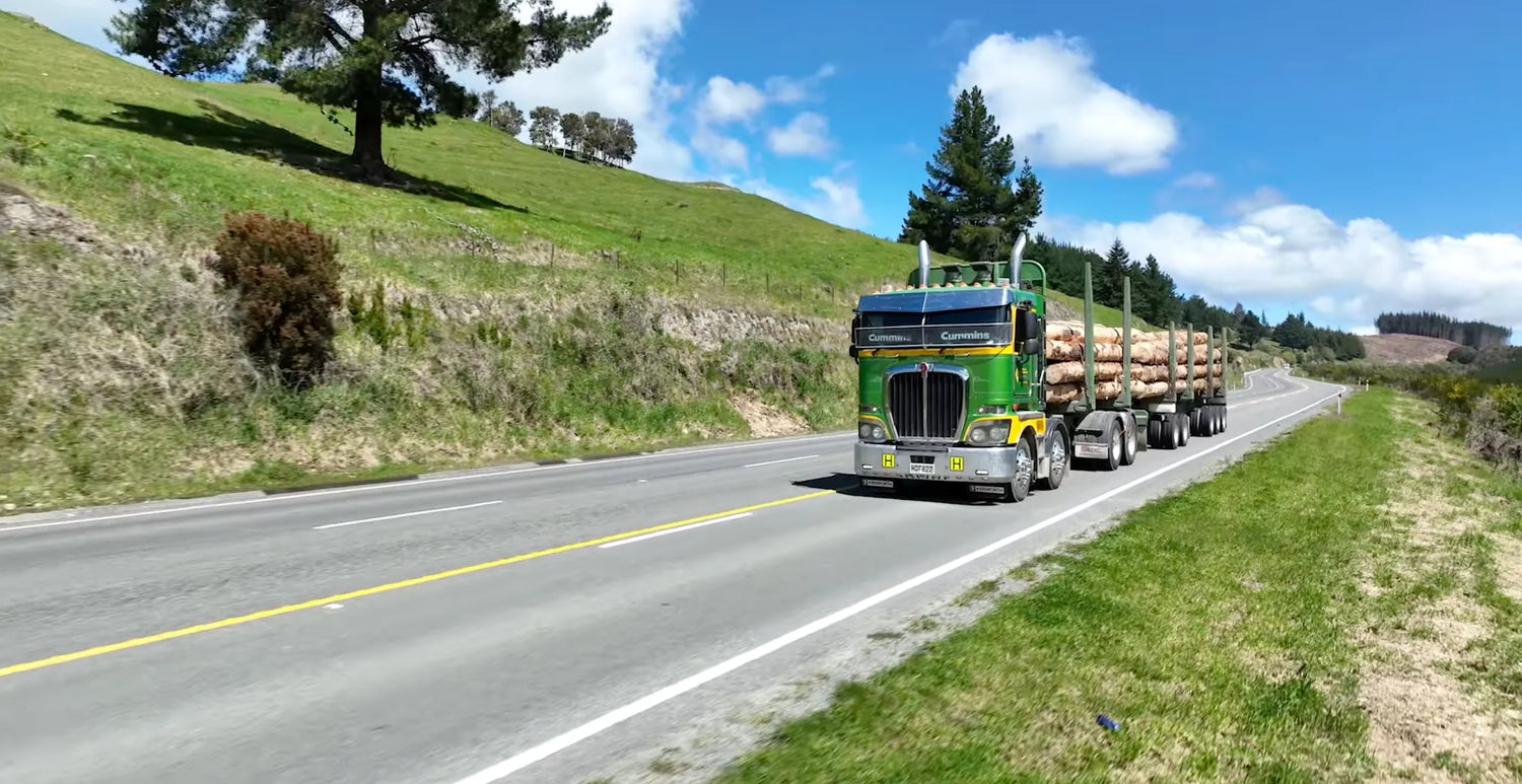 Stuart Drummond Transport: Built for the Job, Built Kenworth hauling logs on a scenic road.