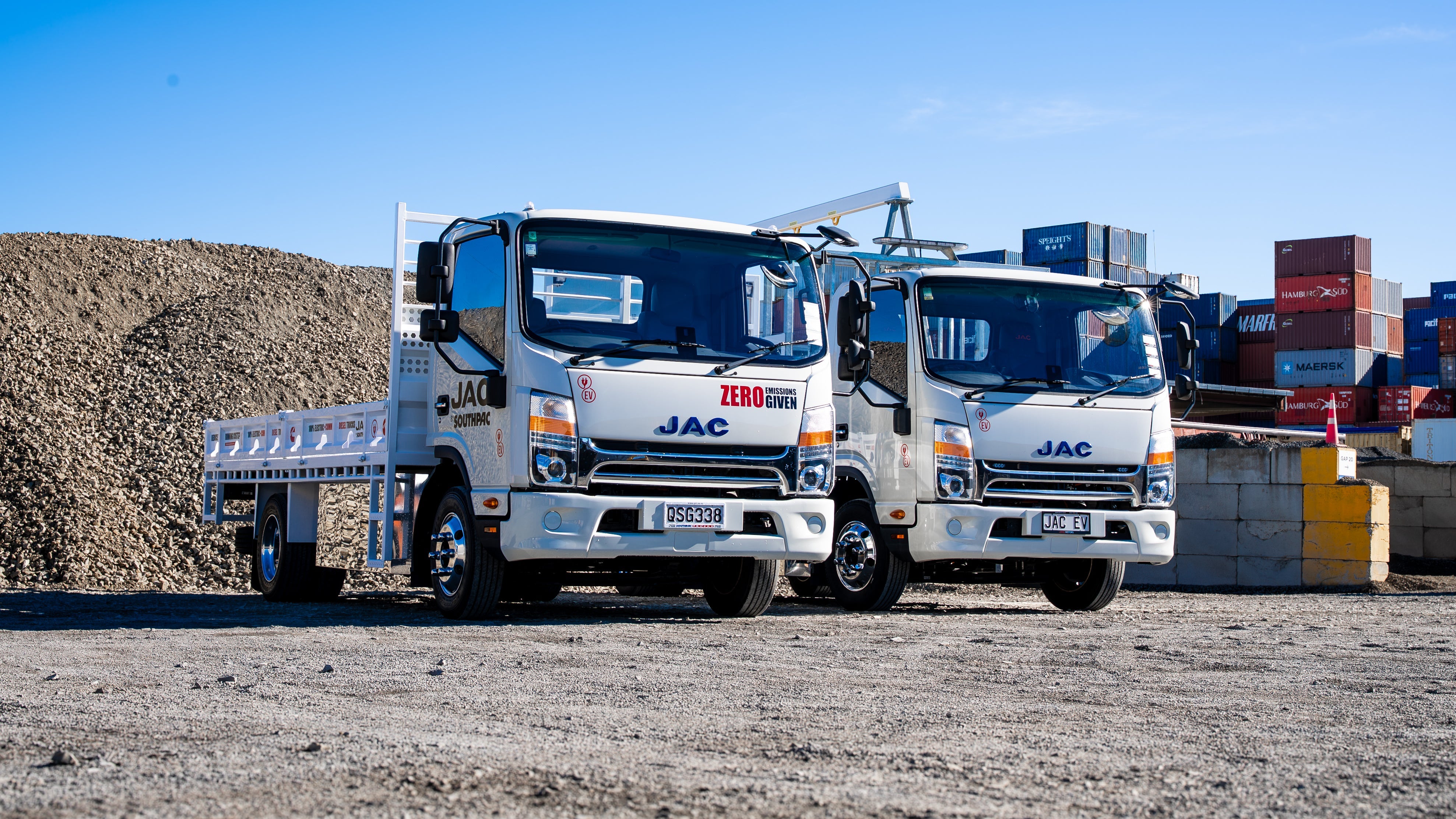 Two JAC trucks parked at a construction site showcasing genuine JAC vehicle parts for durability and performance.