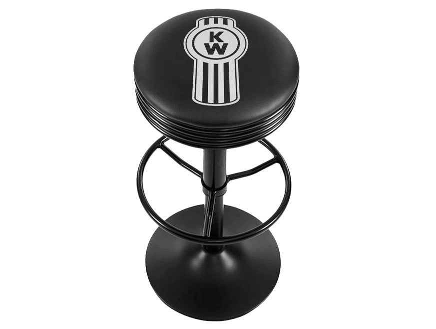 The BARSTOOL KW WHITE BUG is a black barstool with a round seat featuring the white Kenworth logo and vertical stripes. Its durable metal frame with footrest and circular base adds comfort and style to any space.