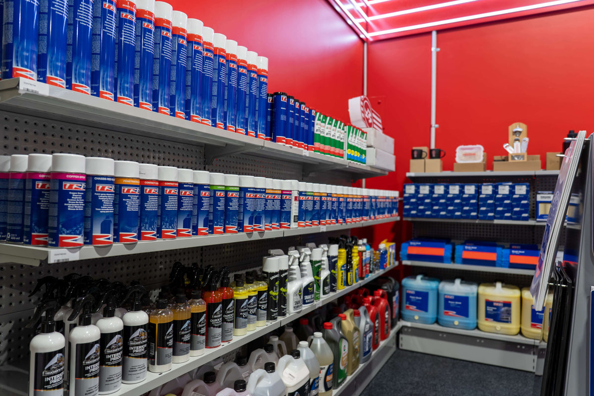 A variety of automotive products displayed on shelves in a shop, featuring cleaning solutions and maintenance items.