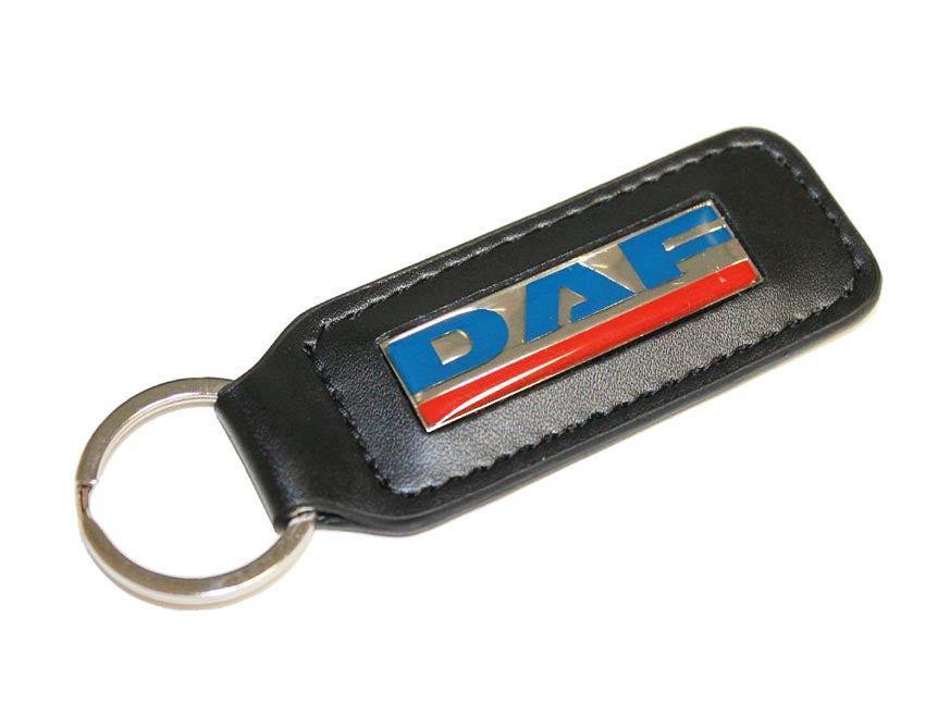 The KEYRING DAF LEATHER is a black leather keyring with a silver ring and a rectangular metal badge showcasing the blue, white, and red DAF logo—ideal for any DAF fan.