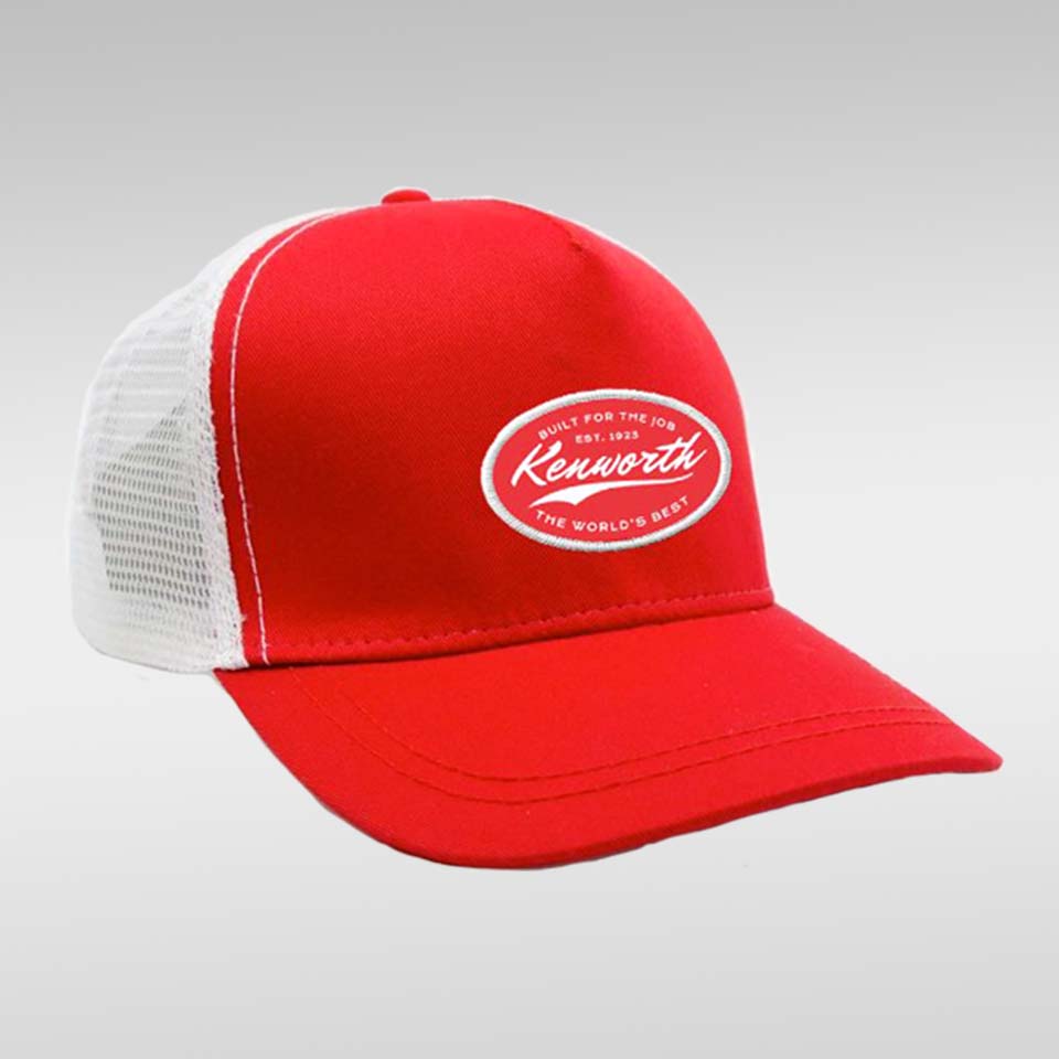 The CAP KW BUILT FOR THE JOB RED is a red and white trucker hat with a mesh back and an oval patch on the front displaying "Kenworth, Built For The Road, Est. 1923, The World's Best" in bold white text.