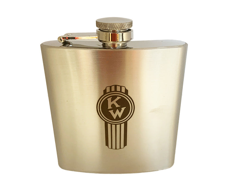 The HIP FLASK KW S/STEEL features stainless steel construction, a screw cap with hinged arm, and an engraved circular Kenworth vintage logo with vertical lines on the front—an elegant accessory shown against a white background.