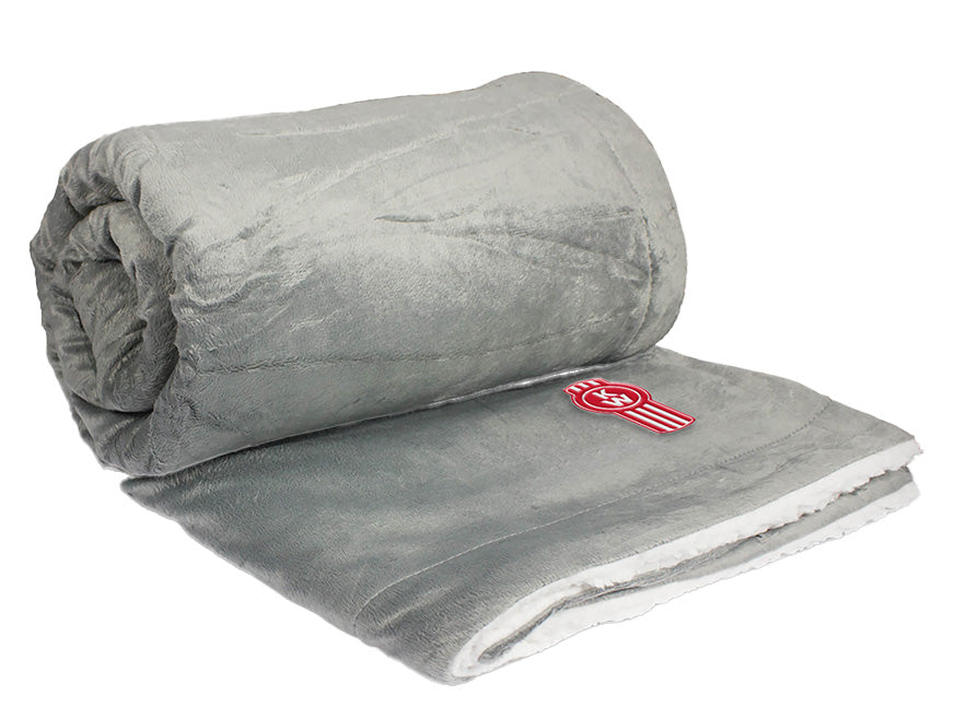 The BLANKET KW GREY/WHIT FLEECE is a soft, light grey fleece blanket with a plush white lining and a red and white circular logo on one corner—perfect for cozy comfort while traveling.