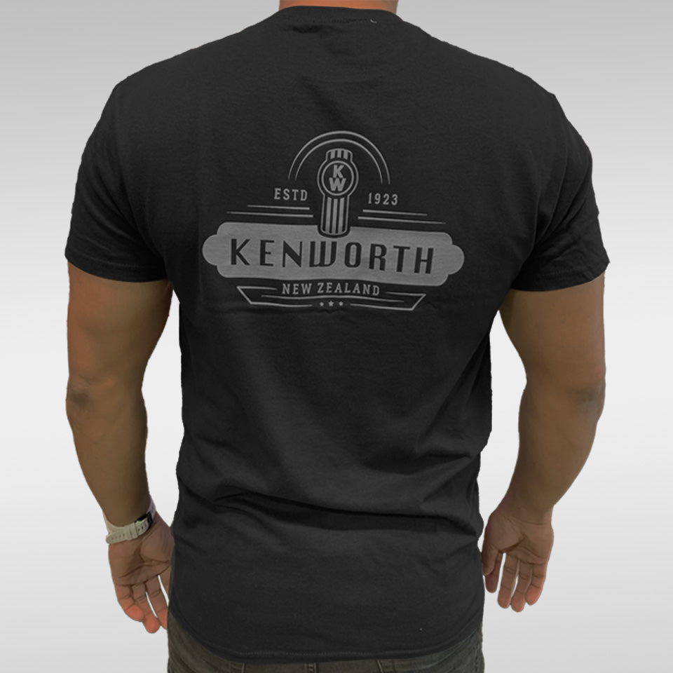 Wearing the TEE SHIRT KW 100 YEARS, featuring a bold Kenworth New Zealand logo with ESTD 1923 and a circular emblem on the back, this person celebrates Kenworth’s century-long heritage.