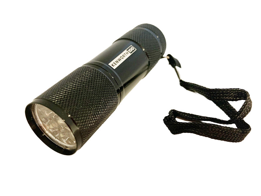 The TORCH KW 100 YEARS is a compact black handheld torch with a textured grip and wrist strap—ideal for honoring Kenworth’s legacy with its discreet anniversary design, shown on a white background.