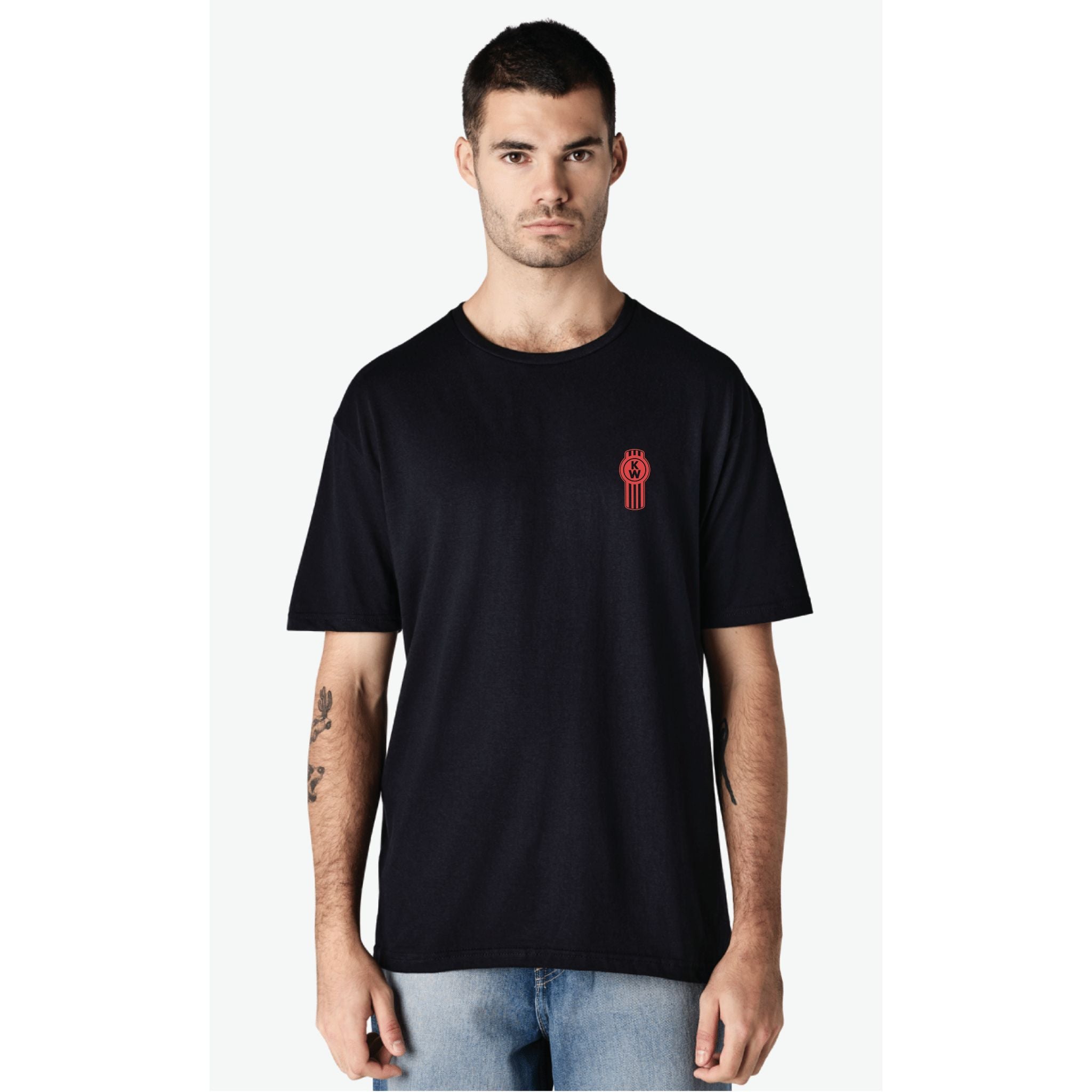 A man with short dark hair and light skin wears a plain black TEE SHIRT KW REDLINE 2XL with a small redline graphic on the left chest and light blue jeans, standing facing forward against a white background.