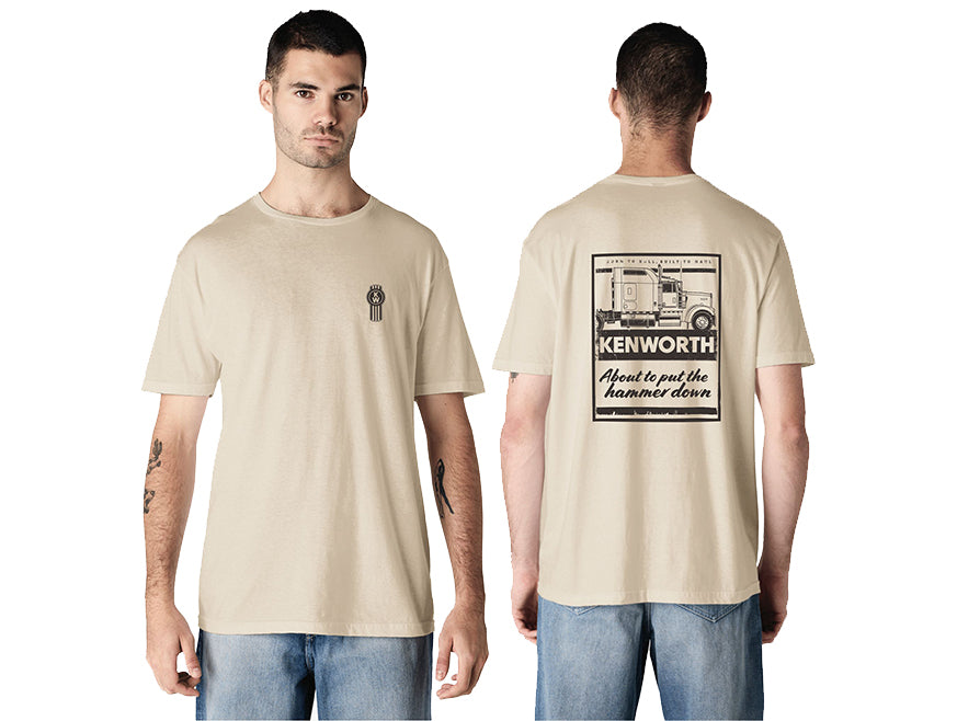 A man wears the TEE SHIRT KW HAMMER, a sand-colored graphic tee with a small circular chest logo and a bold Kenworth truck graphic and "KENWORTH About to put the hammer down" on the back.
