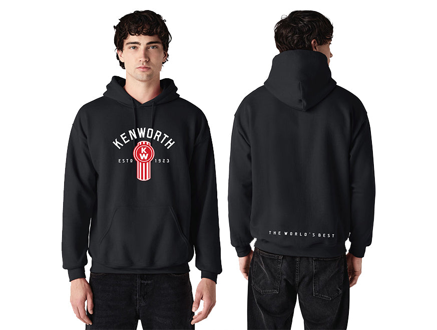 A man wears the HOODIE KW WORLDS, a classic black Kenworth hoodie featuring "Kenworth Estd 1923" and a red logo on the front, "The World's Best" near the hem on the back, with a hood and a spacious front pouch pocket.