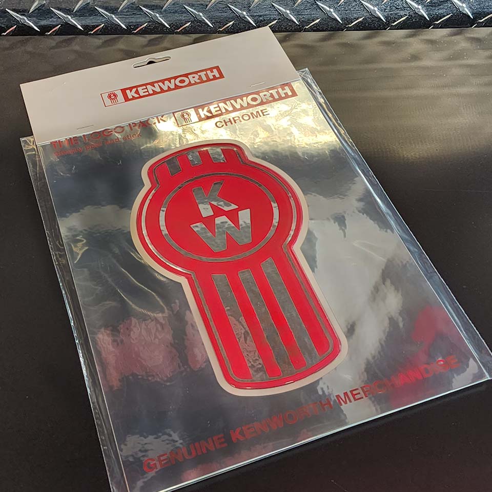 A packaged DECAL BUG LOGO CHROME featuring the red KW Bug Logo, marked as Genuine Kenworth Merchandise, sits on a black diamond plate patterned surface.