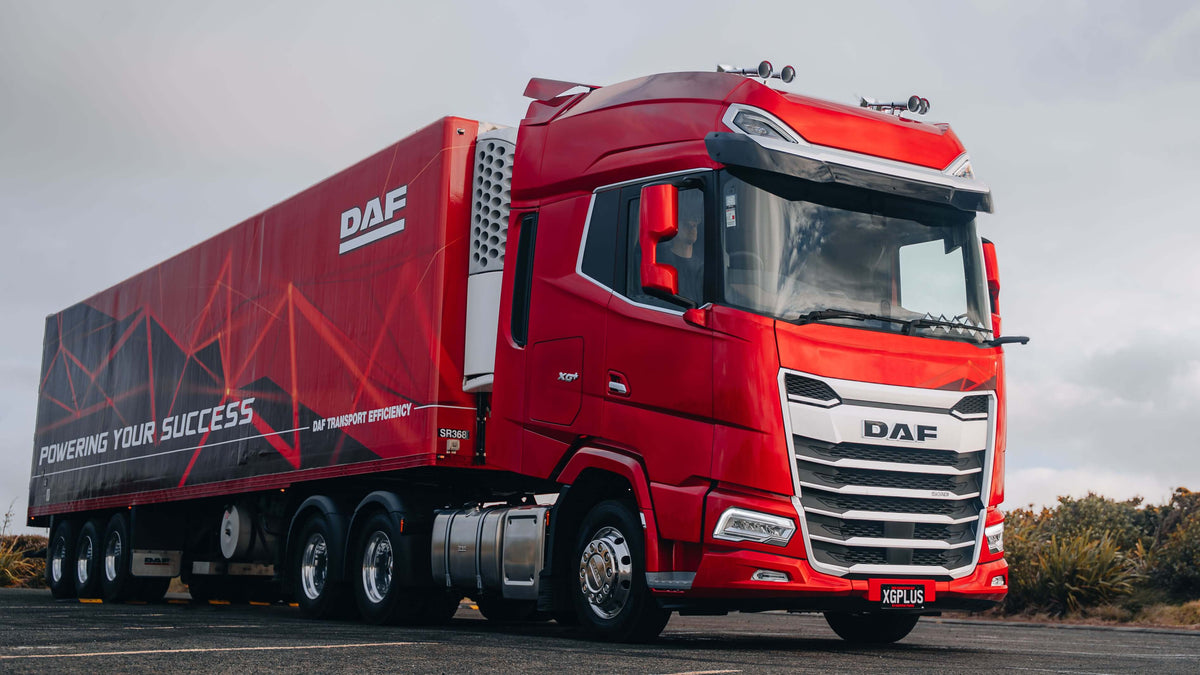 Red New Generation DAF XG+ tractor and trailer on a country road